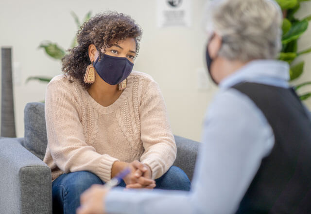 two people with masks sitting opposite each other