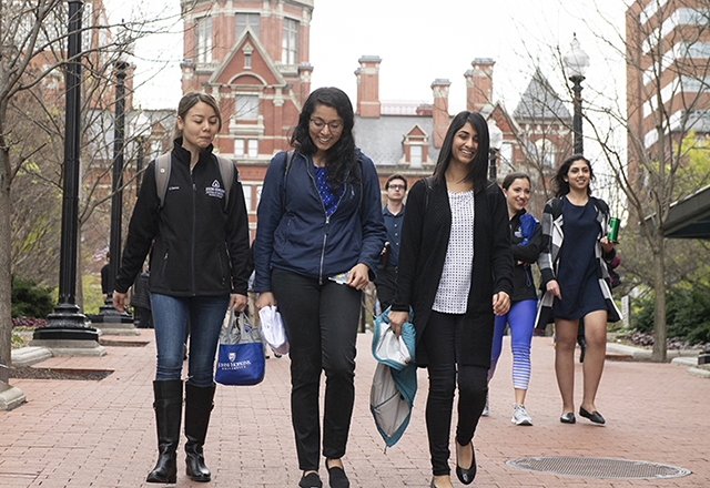 Students walk on the East Baltimore campus, with the Dome in the background.