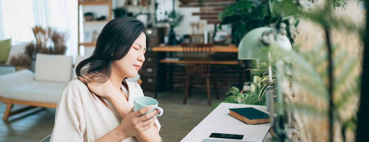 Woman suffering from neck pain while working from home.