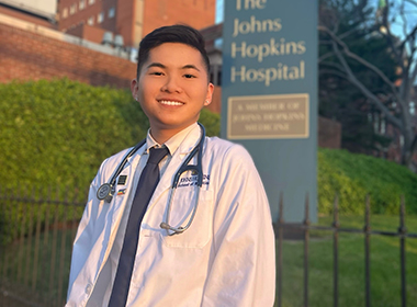 andrew ly smiling in front of johns hopkins hospital