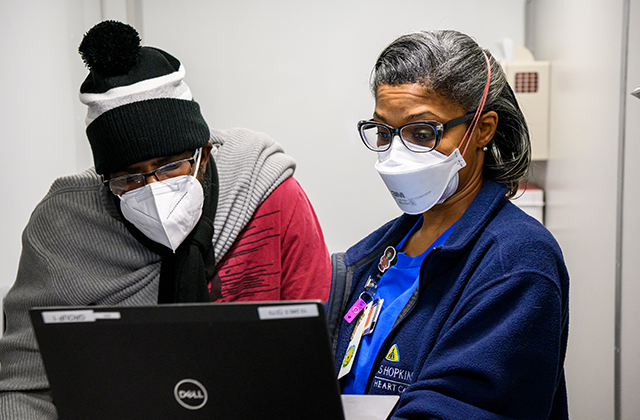 A CIAA Fan Fest attendee looks at information with a member of the mobile vaccine team.