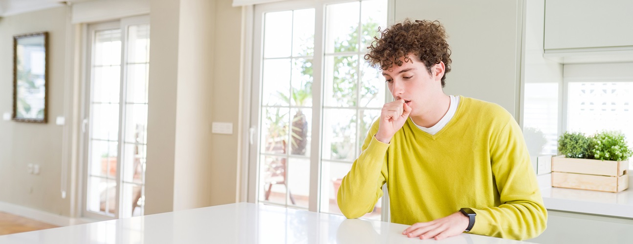 young man coughing at table