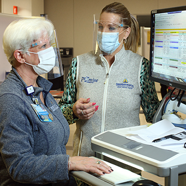 Sarah Rasmussen, R.N., and Michelle Christ, physician liaison, review the day’s vaccination schedule.