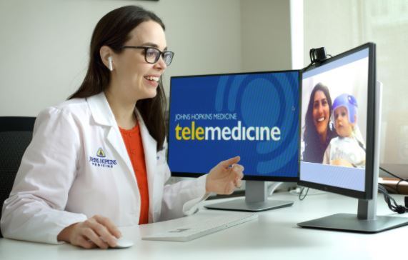 doctor smiling at computer during telemedicine visit