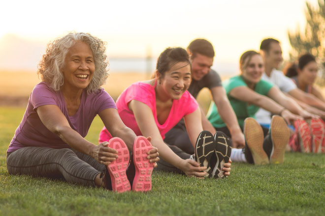 Group of older adults stretching in a grassy field.