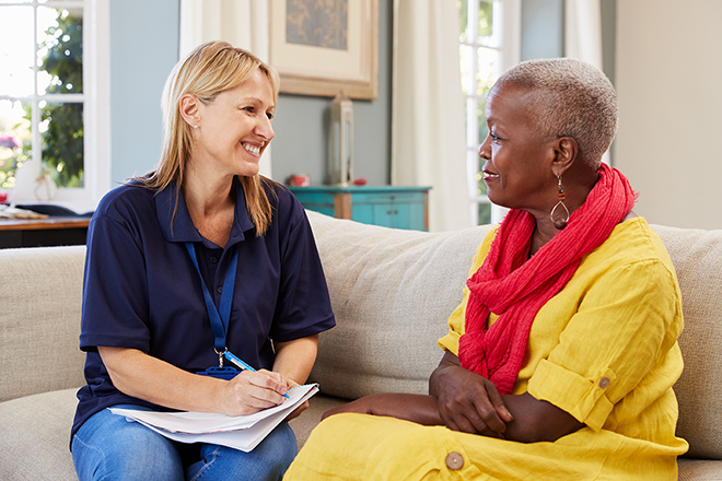 Patient and care giver sitting on couch talking.