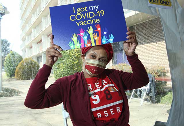 Community member holding a sign that reads I got my COVID-19 vaccine.