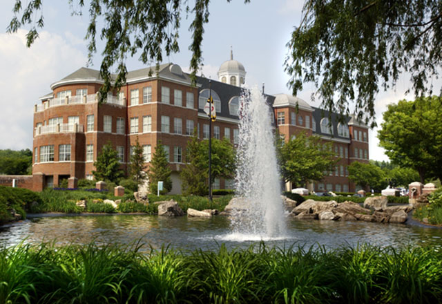 Exterior view of Pavilion I building with pond and water fountain in front.