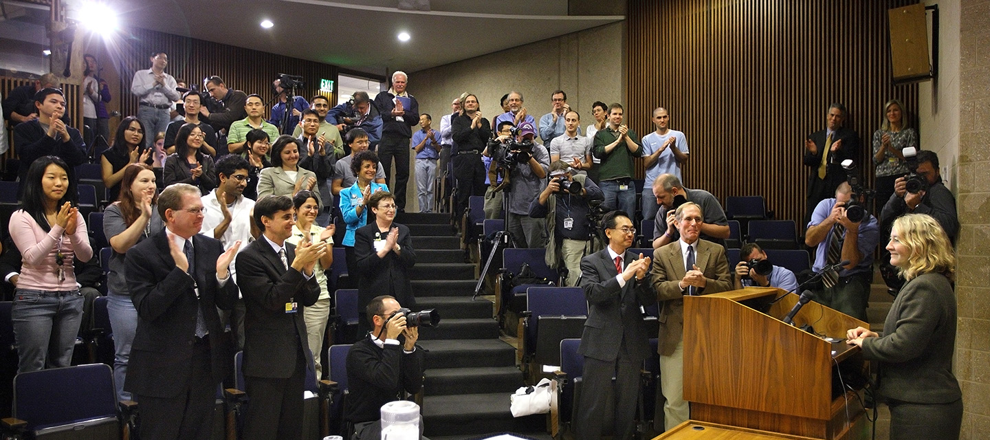 Dr. Greider stands at a podium in front of an audience.