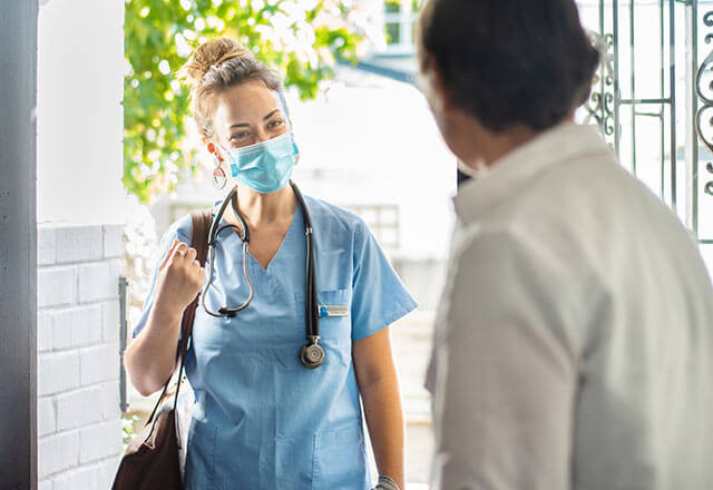 A Home Care employee stands holding oxygen tanks.