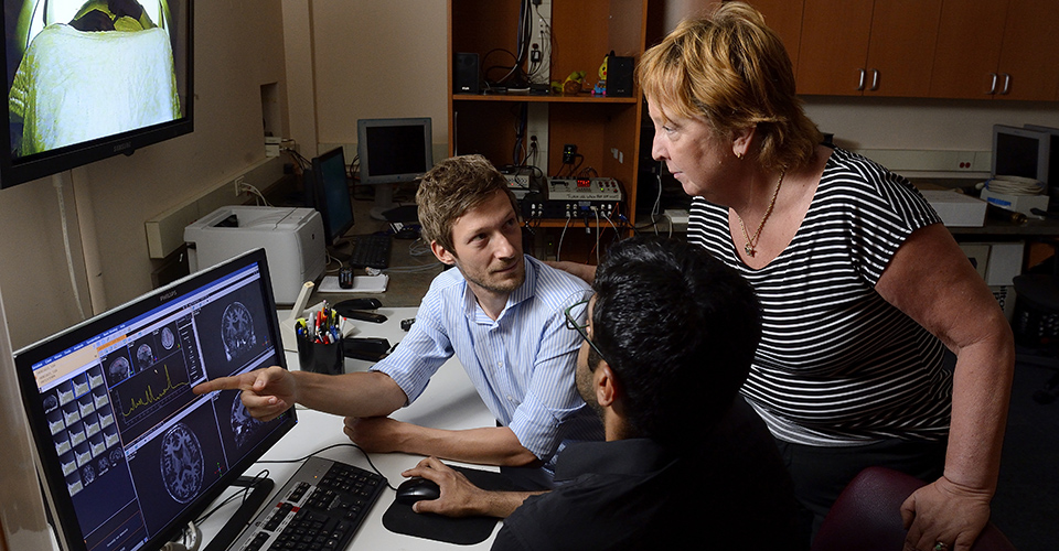 Three people looking at data on a computer screen.