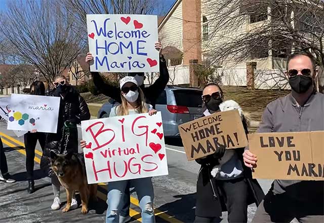 Maria's family and friends holding signs, welcoming her home.