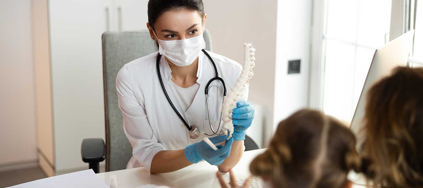 Pediatric orthopaedic doctor discussing with patient wearing PPE.