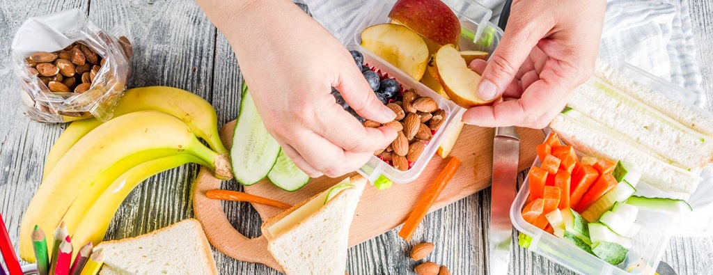 Lunch spread with bananas, a sandwich, almonds and vegetables