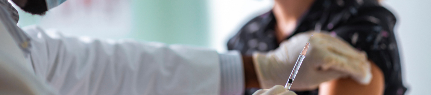 A close-up of a patient receiving a COVID-19 vaccine from a healthcare professional.