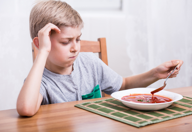 A young boy picks at his food.