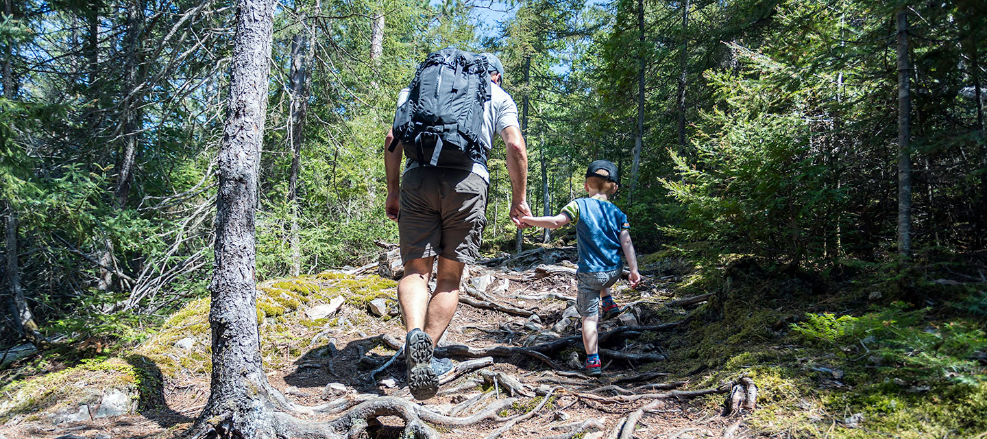 A father and son hike uphill while holding hands