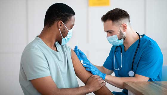 A provider vaccinates a patient in their arm.