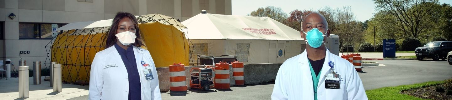 Two doctors standing outside a COVID testing tent.