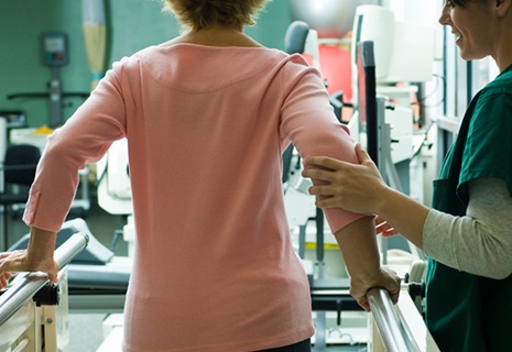 Woman learning to walk again with the help of a physical therapist