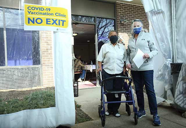 Healthcare provider escorting eligible community member to walk-in station.