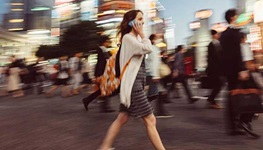 Woman walking on a busy crosswalk while chatting on the phone.