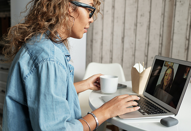 Una mujer usa una computadora para hablar con su amiga.