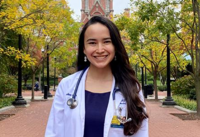 School of Medicine student Carolina Lopez-Silva smiling in a white jacket in front of the Dome building