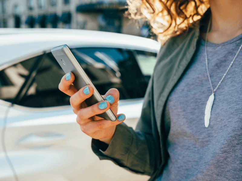 person outside of their car checking in on their phone