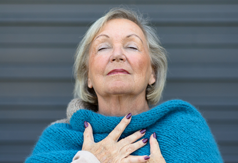 An older woman inhales deeply.