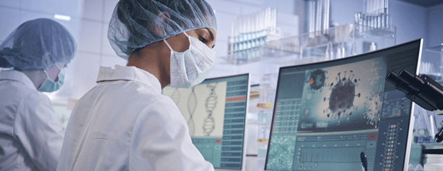 Scientists working at computers, wearing masks.