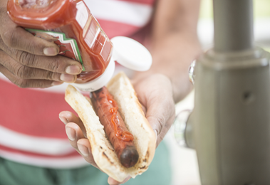 A person puts ketchup on their hotdog.