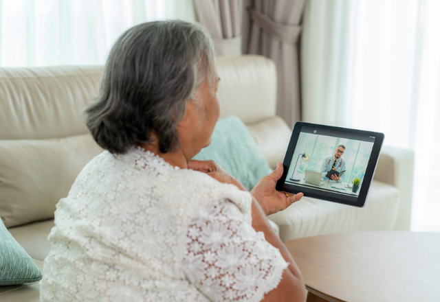 woman holding her throat during a telemedicine appointment